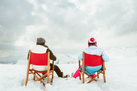 Couple relax sit on chairs in snowy ski resort with beer bottle, concept of leisure, winter holiday, relaxation, carefree lifestyle, freedom, cozy outdoor relaxation momentの写真素材