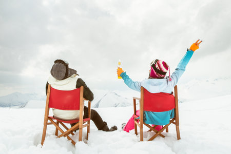 Couple relax sit on chairs in snowy ski resort with beer bottle, concept of leisure, winter holiday, relaxation, carefree lifestyle, freedom, cozy outdoor relaxation momentの写真素材