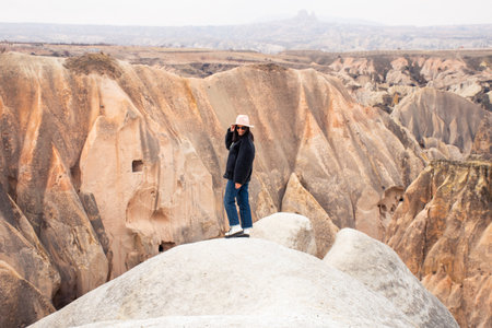 Happy tourist girl explore visit Cappadocia enjoying nature wonderful formations stand in Red Rose Valley in Kapadokya. Traveler explorer influencer enjoy freedom carefree lifestyle conceptの写真素材