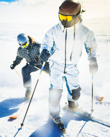 Two advanced young skiers having fun on alpine slope demonstrates an extreme carving skiing style in...