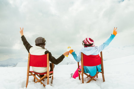 Couple relax sit on chairs in snowy ski resort with beer bottle, concept of leisure, winter holiday, relaxation, carefree lifestyle, freedom, cozy outdoor relaxation momentの写真素材