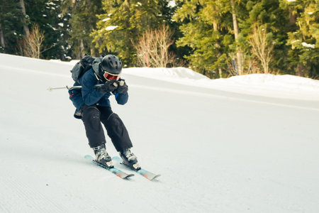 Close up freeze motion skier wearing helmet goggles carving on downhill snowy slope pine forest...