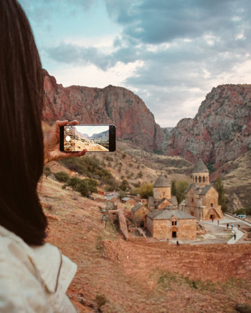 Close up woman stand on viewpoint take photograph of famous landmark Noravank orthodox monastery in...