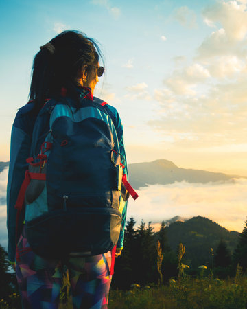 Backpacker standing on slope in Adjara Georgia overlooking morning clouds and Caucasus mountain range in golden sunrise lightの写真素材