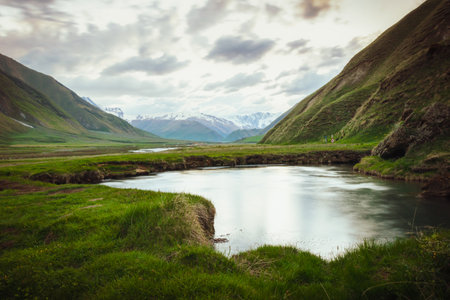 Scenic Truso Valley in Georgia with winding river, green meadows, and Caucasus mountains in background, popular hiking and trekking destination near Kazbegi, eco tourism and nature landscape.の写真素材