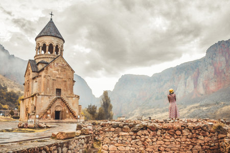 Pretty carefree Tourist woman stand on viewpoint admires view famous Armenian monastery of Noravank. Travel and tourism concept. Top popular travel explore destination caucasusの写真素材