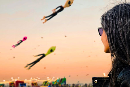 Doha, Qatar - 22nd January, 2026: Woman spectator watching colorful giant kites flying above public park during Doha kite festival at sunset. Popular cultural event Middle East lifestyleの写真素材