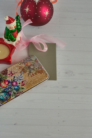 A candle decorated with a snowman, a red Christmas ball with silver stars and a beautiful gift box...