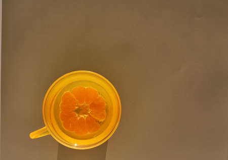 Tangerine is cut in half in an orange cup with water, on a light background