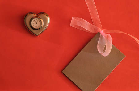 Concept for valentine's day. A Valentine card and a heart-shaped clock on a red background with space for text or logo.の写真素材