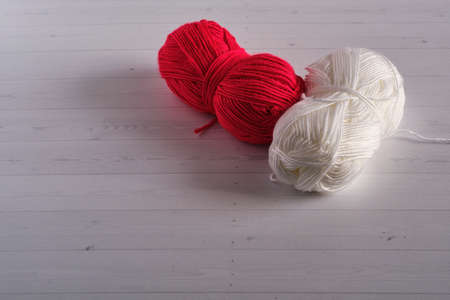 two skeins of yarn for knitting: red and white on a light backgroundの写真素材
