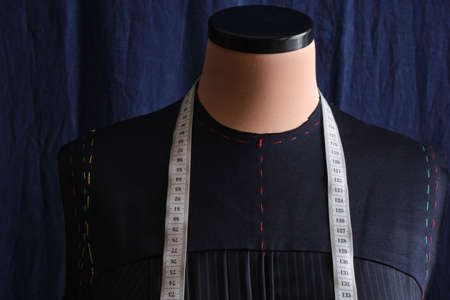 Semi-ready blue dress with tailor's measuring tape on mannequin