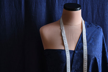 Fashion, dressmaking or tailoring concept. New model applying silk fabrics blue cloth on mannequin...