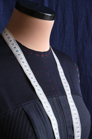 Semi-ready blue dress with tailor's measuring tape on mannequin