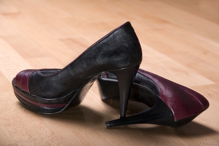pair of duo color high heels side by side on light wooden floorの写真素材