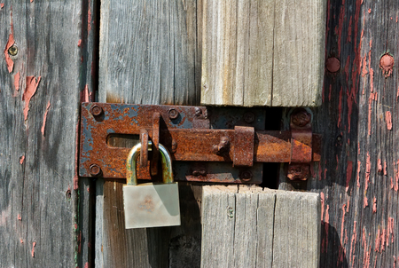 An old rusty padlock on wooden barn doorの写真素材