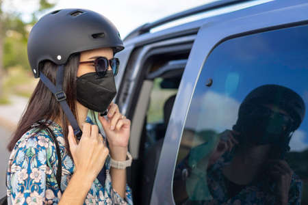 A woman in a mask unbuckling her helmetの写真素材