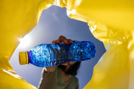 Unrecognisable woman recycling a blue plastic bottleの写真素材