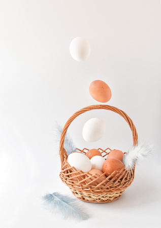Easter composition. The eggs of natural color falling in a basket. On a white background. Happy Easter. Front viewの写真素材