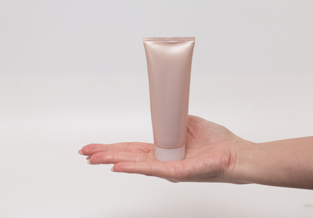 Female hand holding a cream tube, white background. Skin care product. Health and beauty concept.  Female healthcare wellness concept. Front view.の写真素材