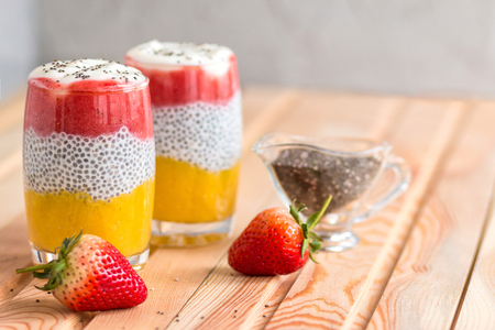 Chia pudding with mango, natural yogurt, chia, wild strawberry in a glass on a wooden table. Healthy dessert, proper nutrition, super food. Top viewの写真素材