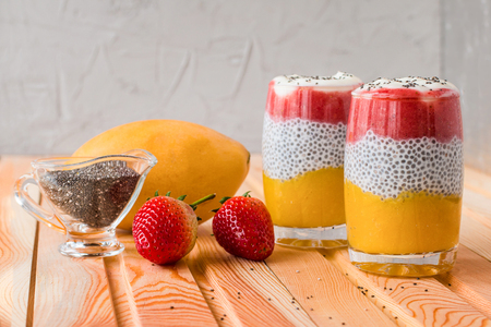 Chia pudding with mango, natural yogurt, chia, wild strawberry  in a glass  on the table laid by burlap. Healthy dessert,  super food. Front viewの写真素材