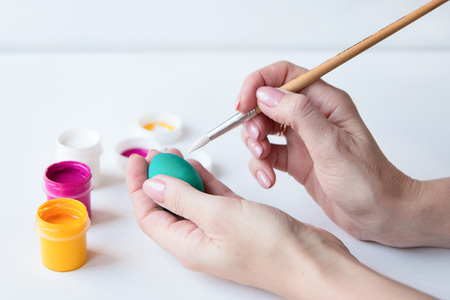 The woman drawing Easter eggs on a white table. Happy Easterの写真素材