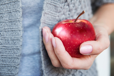 Red mature juicy apple in female hands. Health. Healthy food. Front viewの写真素材