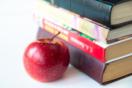 Red mature juicy apple near books. On a white table. Front viewの写真素材