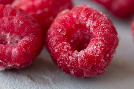 The frozen raspberry berries in hoarfrost on a gray concrete background. Close up. Macro. Front viewの写真素材