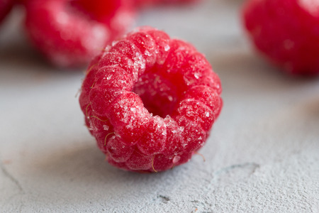 The frozen raspberry berries in hoarfrost on a gray concrete background. Close up. Macro. Front viewの写真素材