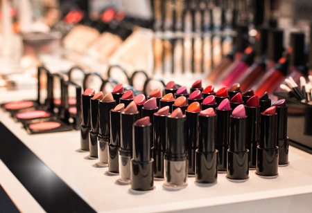 Different colors of lipstick and eye shadow on the shop window in the cosmetic store. Test sample. selective focus. Front viewの写真素材