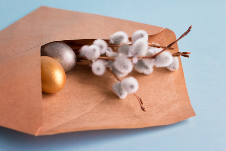 Gold and silver Easter eggs and branches with branches of a willow in a post envelope on a blue background. Easter concept. National holiday celebration concepts. Happy Easter. Copy space. Front viewの写真素材