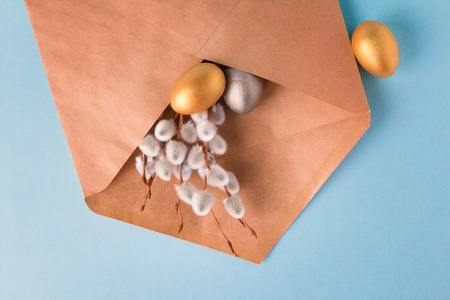 Gold and silver Easter eggs and branches with branches of a willow in a post envelope on a blue background. Easter concept. National holiday celebration concepts. Happy Easter. Copy space. Top viewの写真素材