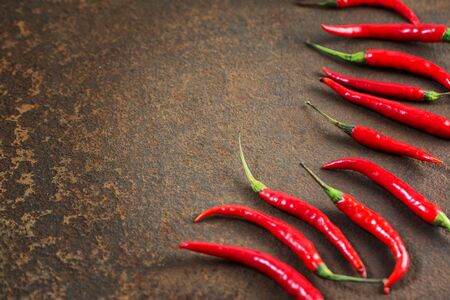 Pods of hot red pepper on a rusty metal surface. Top view. Copy spase