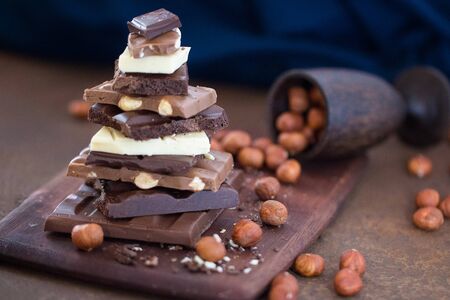 The different grades of chocolate put by the hill on a wooden board, with a filbert  on a rusty...