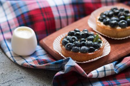 Tartlets with blueberries on the gray table with a checkered napkin. Selective focus. Top viewの写真素材