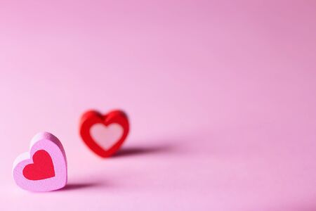 Valentines day concept. Two wooden hearts on a pink surface.  A symbol of love happiness and devotion. Front view. Selective focus. Copy spaceの写真素材