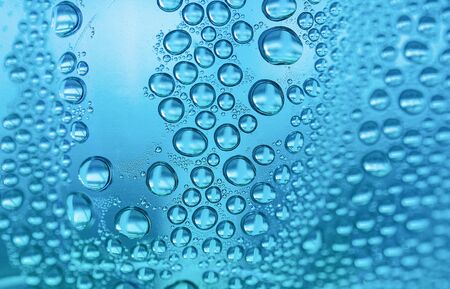 Close up water drops on sky blue tone background. Abstract sky blue wet texture with water drops on glass surface.  Selective focus. Raindrop, realistic pure water droplets, condensate, for creative banner designの写真素材