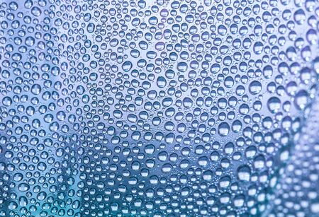 Close up water drops on light lilac tone background. Abstract light lilac  wet texture with water drops on glass surface.  Selective focus. Raindrop, realistic pure water droplets, condensate, for creative banner designの写真素材