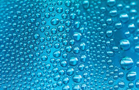 Close up water drops on sky blue tone background. Abstract sky blue wet texture with water drops on glass surface.  Raindrop, realistic pure water droplets, condensate, Selective focus.の写真素材