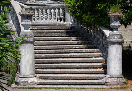Ancient staircase with stone balusters on a background of green vegetation