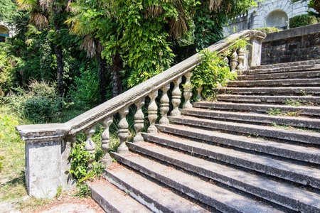 Ancient staircase with stone balusters on a background of green vegetation