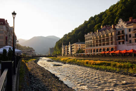 RUSSIA, SOCHI - JULY 16, 2020: view of hotels, cafes, shops, river in the resort of Rosa Khutor. The rays of the evening sunのeditorial素材