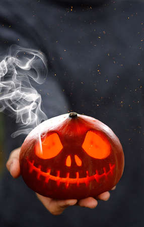 A Smoking pumpkin in a mans hand. Big spooky helloween symbol. Selective focusの写真素材