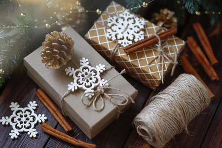 Creative zero waste Christmas concept, handmade gift boxes tied with twine, with Golden fir cones and wooden snowflakes and cinnamon sticksの写真素材