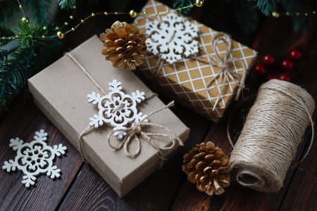 Creative zero waste Christmas concept, handmade gift boxes tied with twine, with Golden fir cones and wooden snowflakes and cinnamon sticksの写真素材