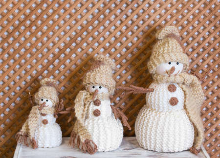 Three toy knitted snowmen in brown hats. Christmas decoration of the interior.の写真素材