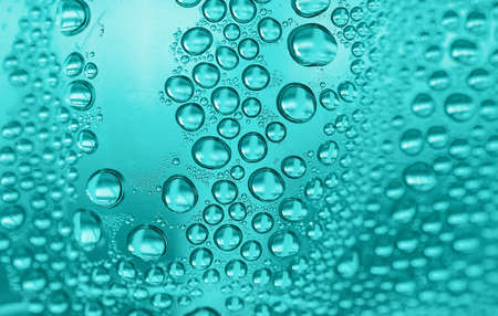 Close up water drops on light green tone background. Abstract light tidewater green wet texture with water drops on glass surface. Selective focus.の写真素材