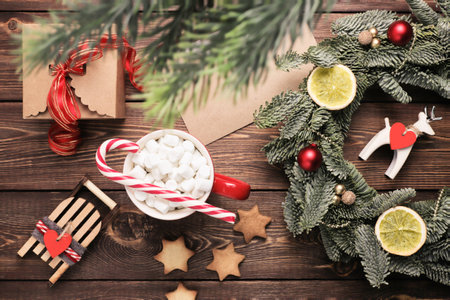 Christmas wreath, gift, coffee mug with marshmallows, envelope and homemade cookies and various Christmas decorations on the wooden table. Rustic christmas wreath, flat lay.の写真素材